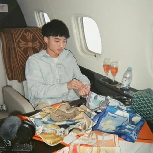 Young man on a private jet with Hermès scarves and champagne